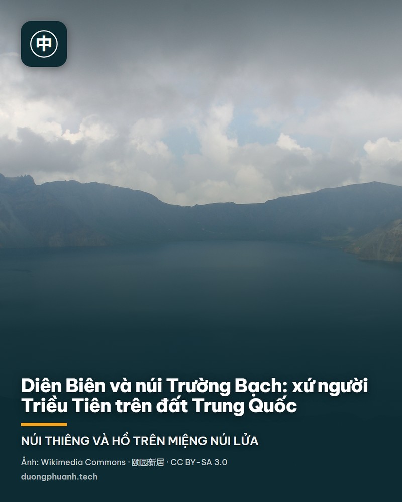 Ảnh chụp từ trên cao khối núi Trường Bạch giữa trời xanh đậm: chóp núi lửa phủ đất nâu đỏ với những vệt tuyết trắng, ở giữa là mặt hồ Thiên Trì xanh thẫm hình bầu dục nằm gọn trong vành miệng núi lửa, phía dưới là rừng già sẫm màu trải dài tới đường chân trời mờ sương