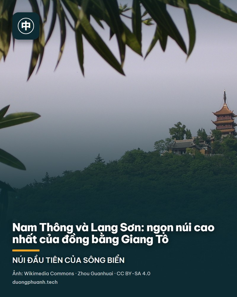 Ngọn Lang Sơn phủ kín cây xanh nhìn từ dưới chân núi: đỉnh núi nổi lên giữa nền trời nhạt với ngôi chùa mái ngói đỏ và cây tháp nhiều tầng trên đỉnh, sườn núi rậm rạp, phía trước là những cành lá và hoa trắng của cây trúc đào làm khung cho bức ảnh.