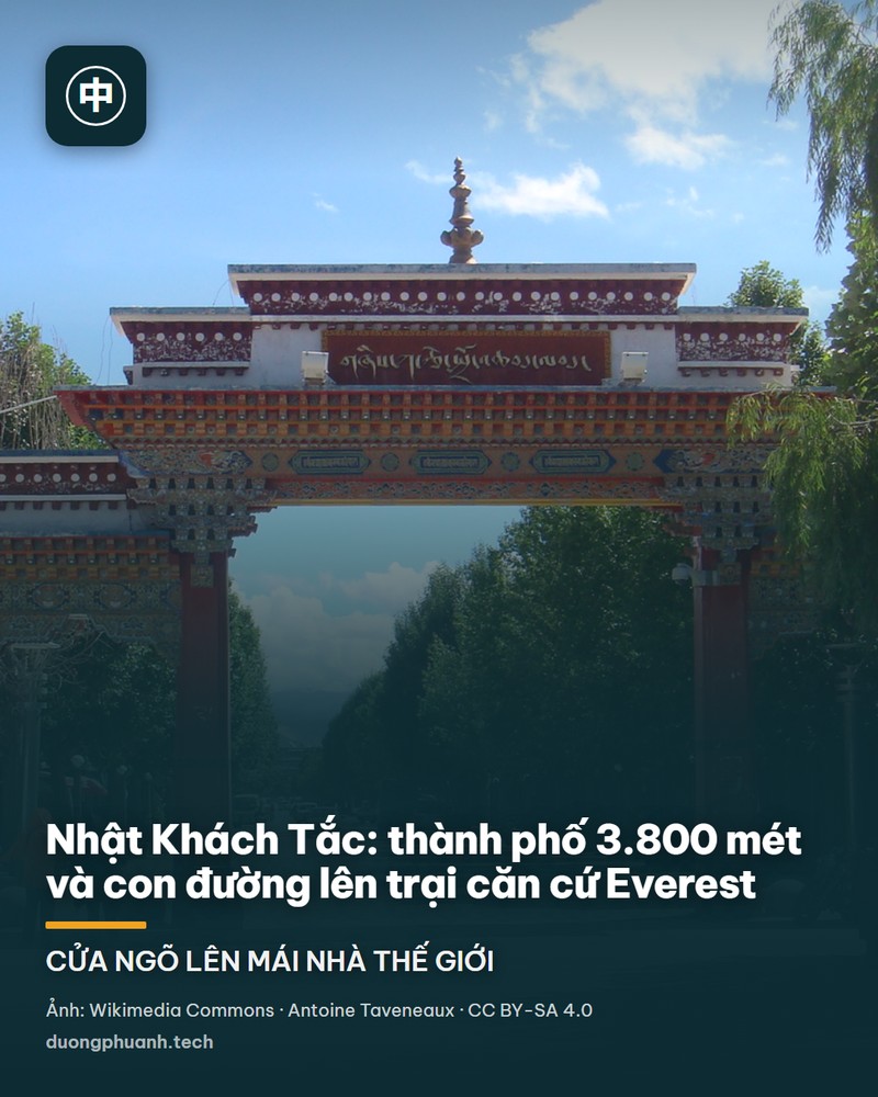 Đỉnh Everest nhìn từ phía bắc: khối núi tuyết trắng hình chóp phủ kín băng tuyết nổi bật trên nền trời xanh thẫm, phía trên đỉnh có một vệt mây trắng nhỏ; phía trước là thung lũng sỏi đá nâu xám với các doi đất, con đường mờ chạy dọc đáy thung lũng và những đám cỏ khô thưa.