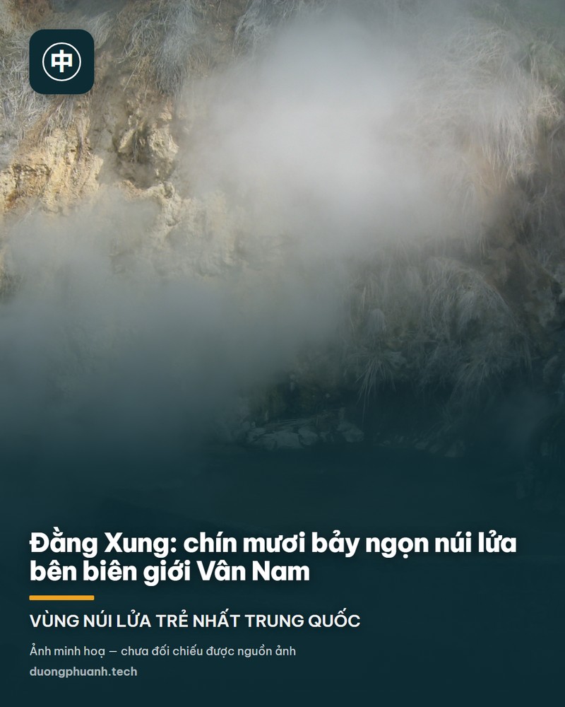 Miệng núi lửa Đại Không Sơn ở Đằng Xung nhìn từ trên vành xuống: lòng chảo rộng phủ kín cây xanh mướt, viền miệng núi là rừng thông, phía trên là nền trời xanh có mây trắng và vài ngọn núi xa mờ màu xanh đậm.