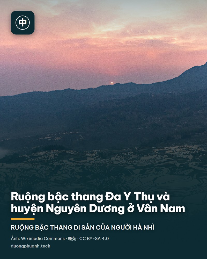 Toàn cảnh ruộng bậc thang Đa Y Thụ ở Nguyên Dương lúc bình minh: các thửa ruộng ngập nước uốn theo đường đồng mức phản chiếu ánh vàng cam trên nền núi tối, phía sau là dãy núi lớn có mây phủ đỉnh và những tia nắng xuyên qua; một cụm làng nằm bên sườn phải.