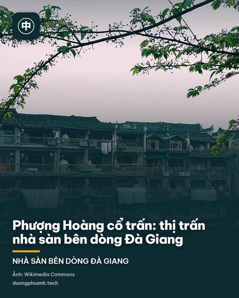 Nhà sàn gỗ của người Miêu và Thổ Gia dựng ven bờ sông Đà Giang ở Phượng Hoàng cổ trấn, tỉnh Hồ Nam: từng dãy nhà nhiều tầng mái ngói xám nhô ra mặt nước trên các cột gỗ, phía xa trên bờ là tháp Vạn Danh nhiều tầng và sườn núi phủ cây xanh, mặt sông phẳng lặng màu lục.