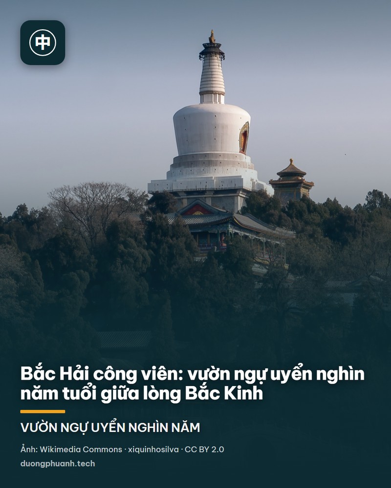 Toàn cảnh hồ Bắc Hải nhìn từ bờ nam: mặt hồ xanh phẳng lặng, cây cầu đá trắng có lan can chạm tròn uốn cong ở bên trái, đảo Quỳnh Hoa phủ cây xanh ở giữa với ngọn Bạch Tháp trắng nhô lên trên, hàng liễu rủ ven bờ, bầu trời xanh trong không mây.