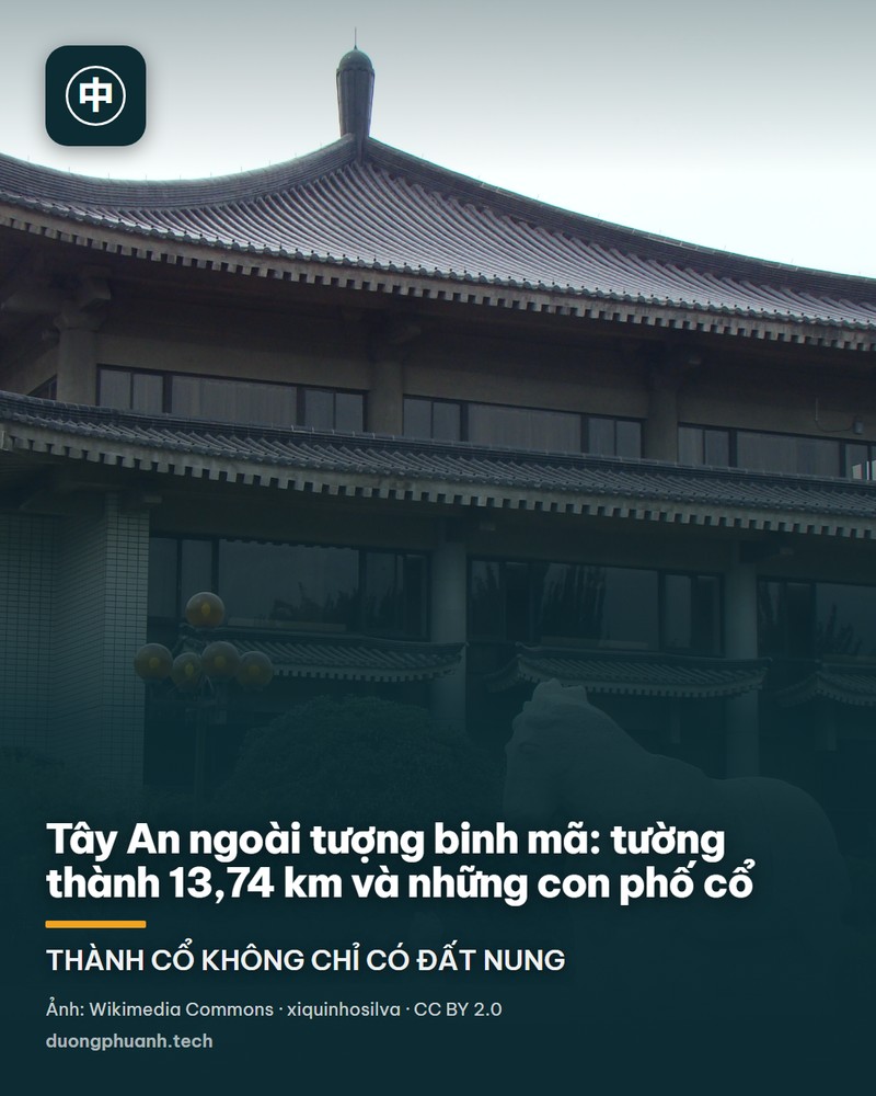 Hai tháp canh góc có mái cong nhiều lớp của tường thành Tây An nhô lên giữa rừng cây xanh mướt; bên dưới là chân tường gạch xám dày và vườn cây, phía xa là những toà nhà cao tầng mờ trong sương.