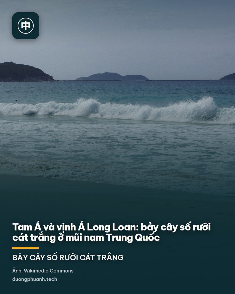 Bãi biển vịnh Á Long Loan trong nắng sáng, cát vàng mịn chạy theo đường cong bờ biển, nước biển xanh ngọc nông nhìn thấy đáy, phía xa là dãy khách sạn trắng nhiều tầng cùng những chiếc dù che xanh dựng ven bờ, sau lưng là núi xanh mờ dưới trời xanh có mây trắng