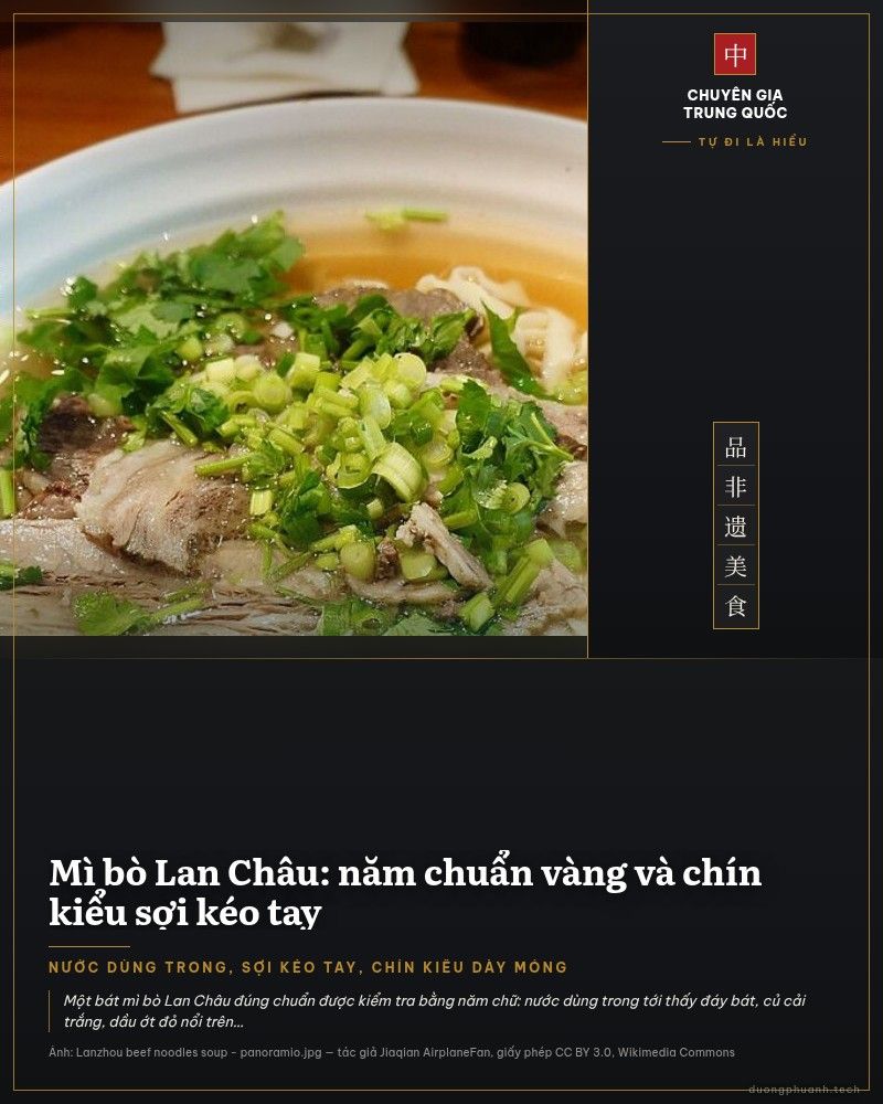 Bát mì bò Lan Châu nước dùng trong, sợi mì dẹt vàng óng, thịt bò thái lát mỏng xếp trên mặt cùng ngò rí xanh và hành lá, đặt trên bàn gỗ.