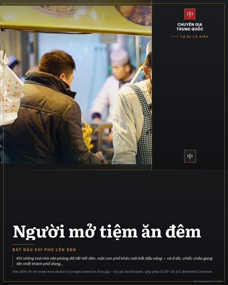 Người bán hàng ăn đêm tại chợ đêm Tây An, Trung Quốc, mặc tạp dề kẻ ô và đội mũ giấy trắng, đứng sau chảo gang lớn đầy thức ăn dưới ánh đèn vàng