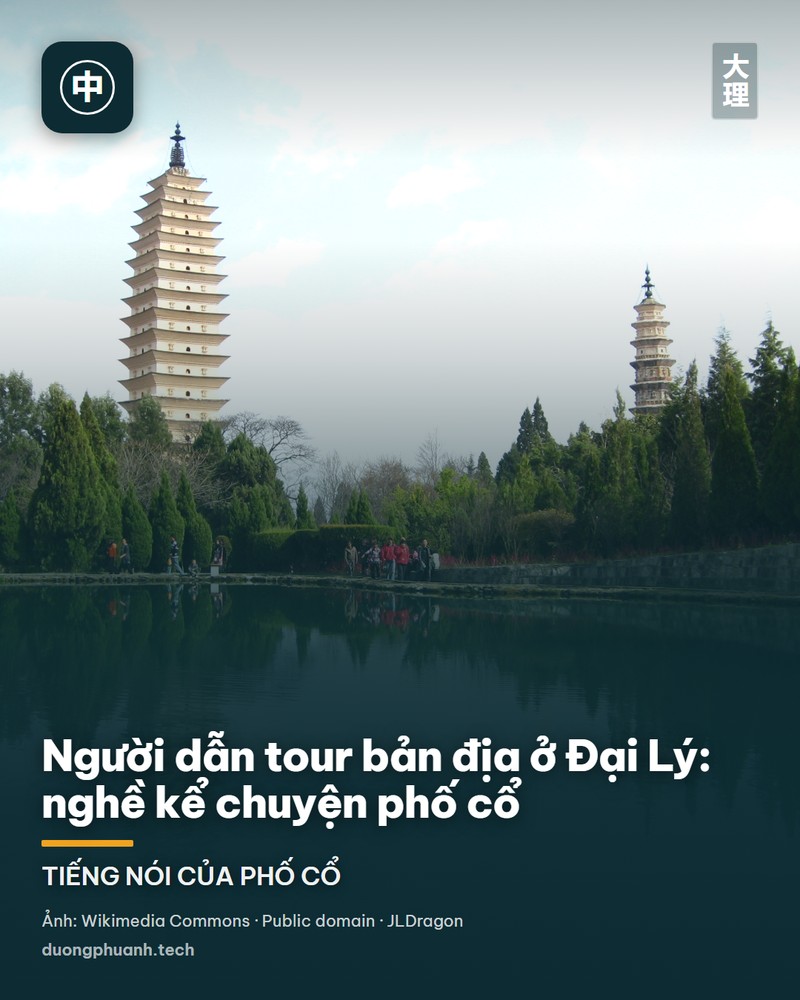 Người hướng dẫn viên đứng trước quần thể đền mái ngói đỏ ở Đại Lý, một tay giơ lên giải thích cho du khách, phía sau là sân đá rộng và núi Thương Sơn.