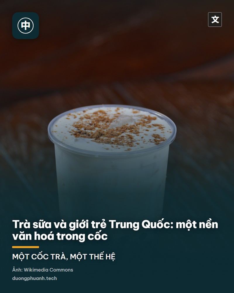 Mặt tiền cửa hàng trà sữa Hỷ Trà với bảng hiệu chữ lớn màu trắng trên nền lam, vách kính lớn và lối vào bằng kính nhìn thẳng ra quảng trường lát đá