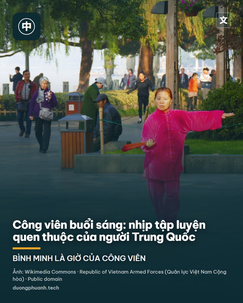 Một phụ nữ mặc bộ đồ lụa màu hồng cánh sen đang múa quạt trong tư thế thái cực quyền trên lối đi lát đá ven hồ, phía sau là hàng liễu, bồn cây và những người đi bộ buổi sớm
