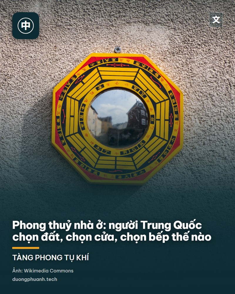 Cận cảnh một tấm gương phong thuỷ hình chữ nhật khung gỗ đỏ treo trên tường gạch, mặt gương vẽ đồ hình bát quái màu đỏ ở giữa, quanh đó là chữ Hán và hình núi non sông nước, phía dưới là cửa ra vào — vật trấn yểm quen thuộc treo trước cửa nhà của người Trung Quốc
