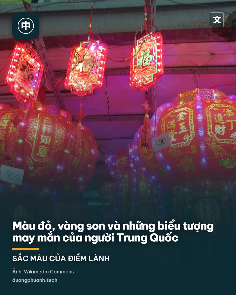 Ảnh cận cảnh những chiếc đèn lồng đỏ truyền thống của người Trung Quốc treo trước nền trời xanh, tua rua vàng buông xuống, lá cây phía sau mờ đi trong nắng